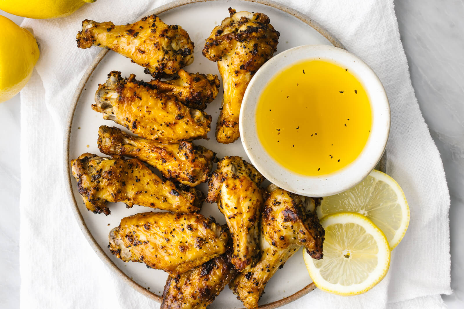 A plate of lemon pepper air fryer chicken wings on a napkin