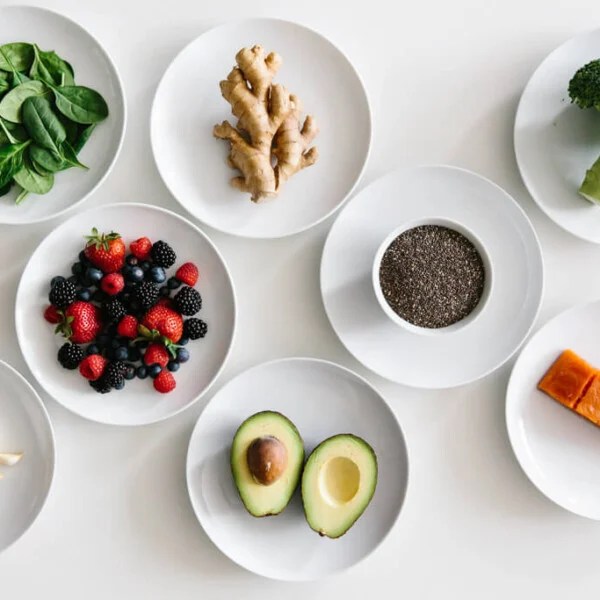 Eight plates of individual anti-inflammatory ingredients on white table.