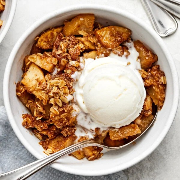 Apple crisp in a bowl with ice cream.