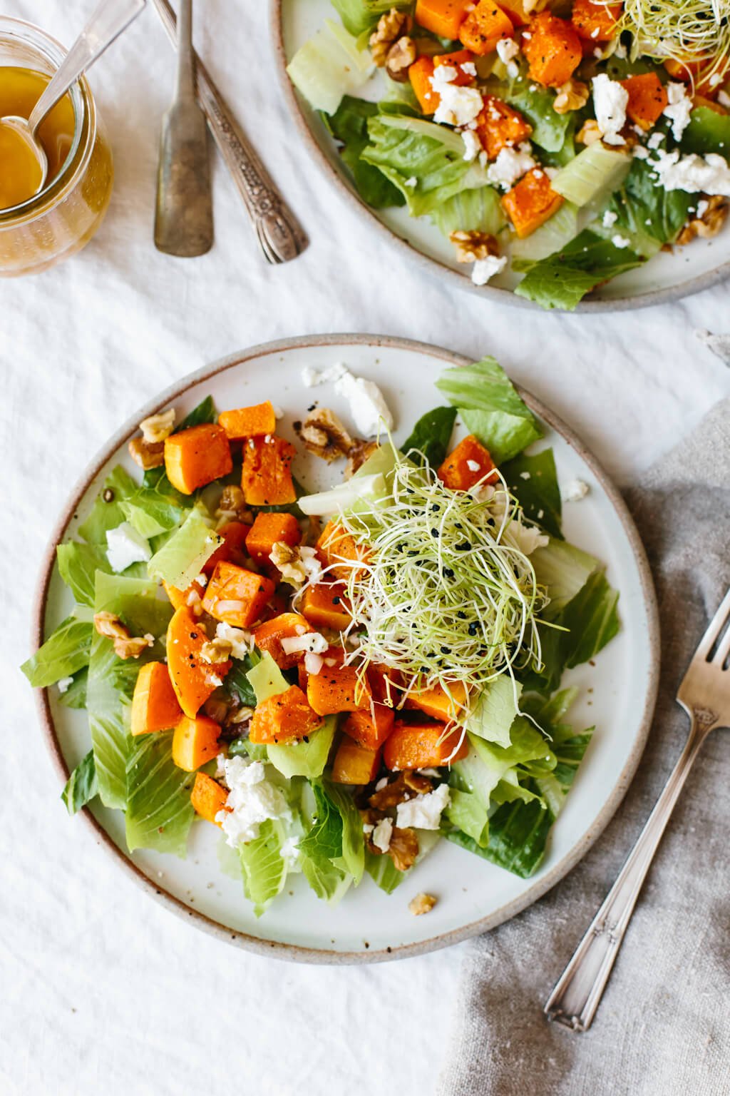 This roasted butternut squash salad is easy and comes together fast! There's just a handful of ingredients including roasted butternut squash, romaine lettuce, goat cheese, walnuts and sprouts but it's packed with flavor for a delicious fall salad recipe.