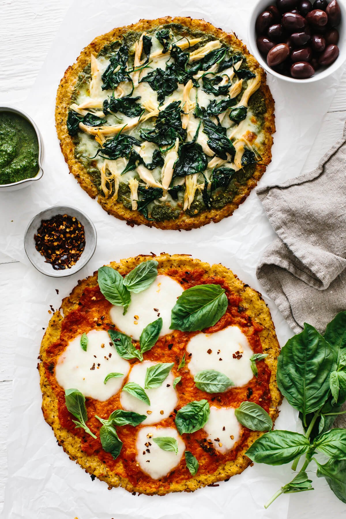 Two cooked cauliflower pizzas.