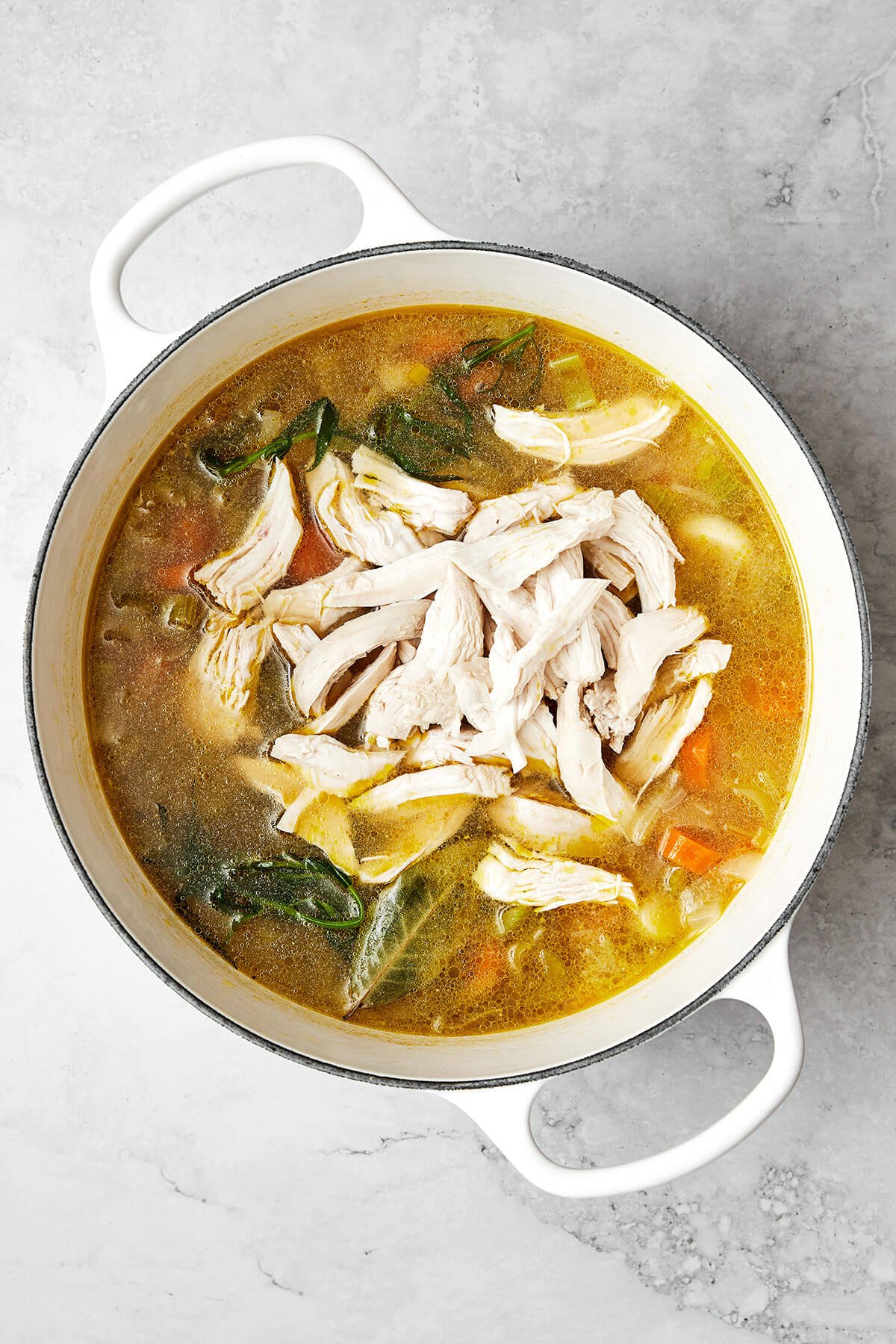 Adding chicken to a pot of chicken soup