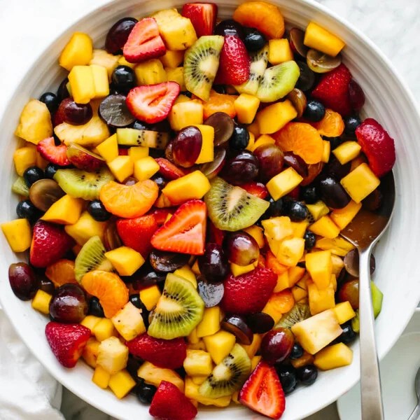 A large fruit salad bowl next to a napkin.