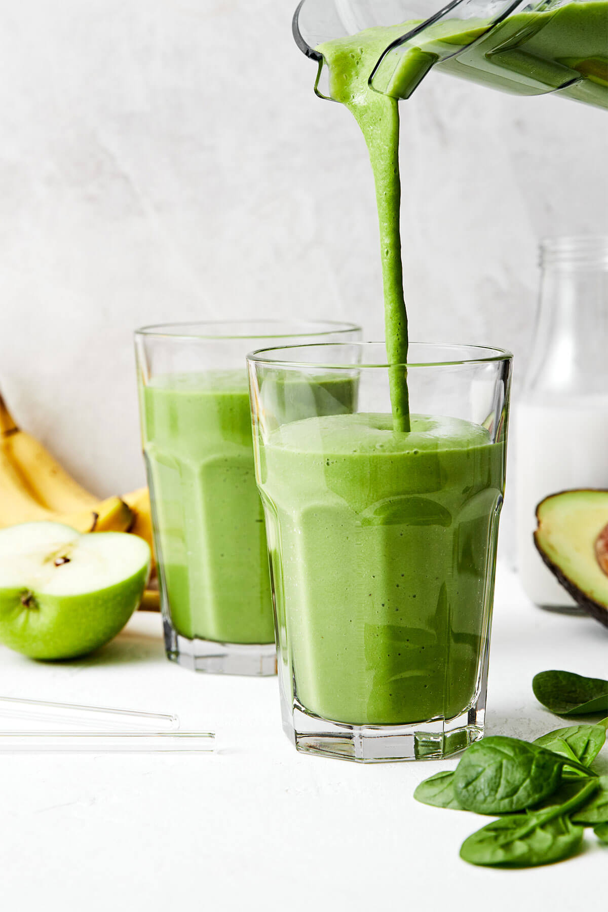 Pouring green smoothie into a cup.