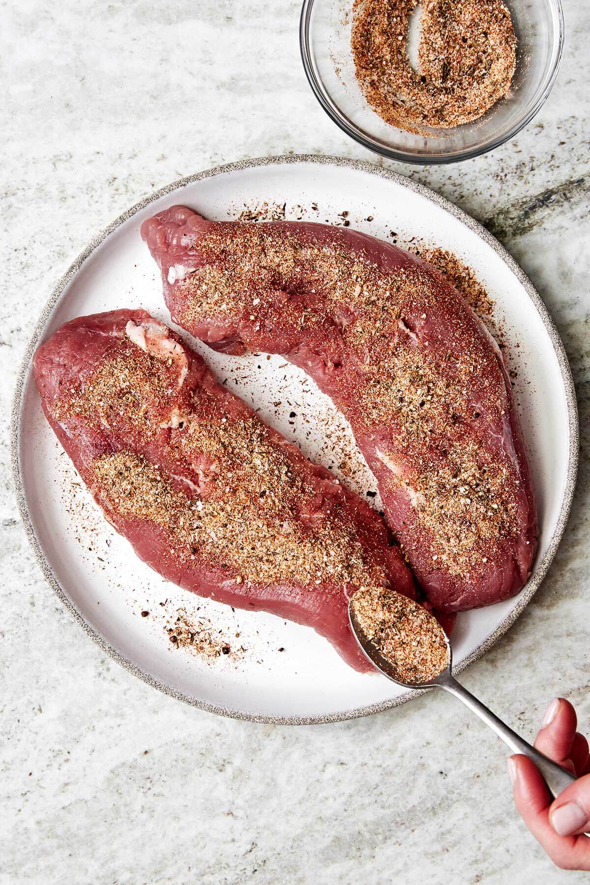 Adding seasoning to pork tenderloin.