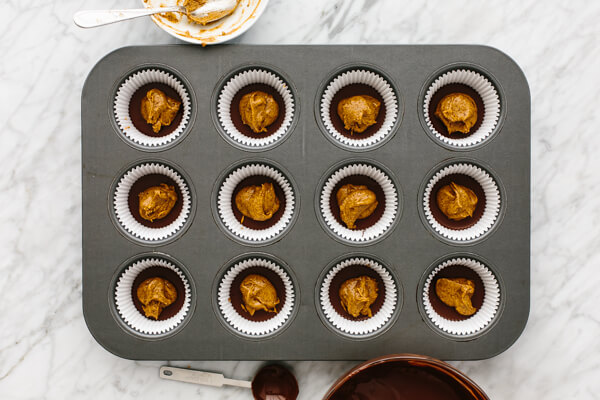 Almond butter being added to muffin tin for almond butter cups.