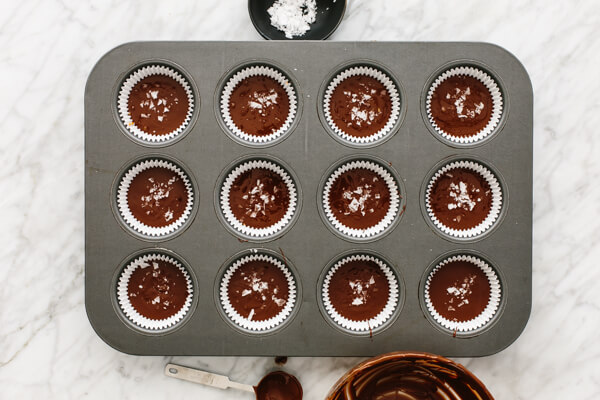 Salt being sprinkled onto to almond butter cups.