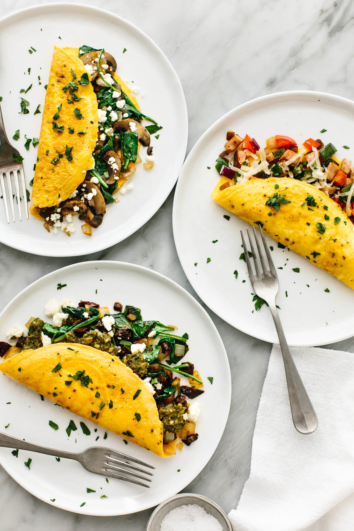 3 omelettes on plates with forks