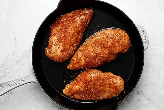 Searing chicken in a skillet.