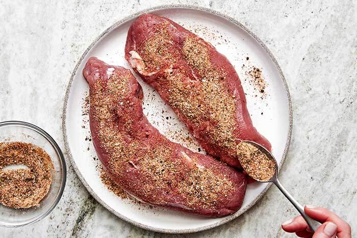 Seasoned pork tenderloin on a plate.