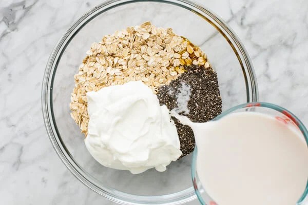 Adding ingredients for overnight oats to a bowl.