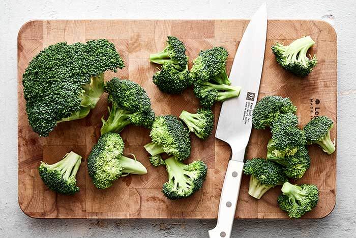 Chopped broccoli florets next to a knife.