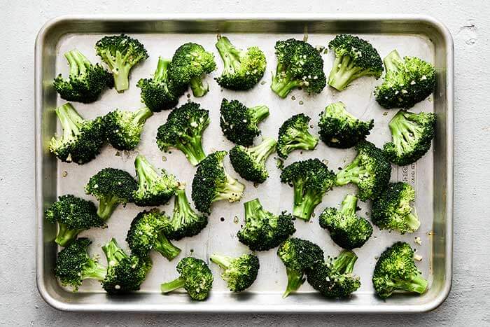 A sheet pan of seasoned broccoli.