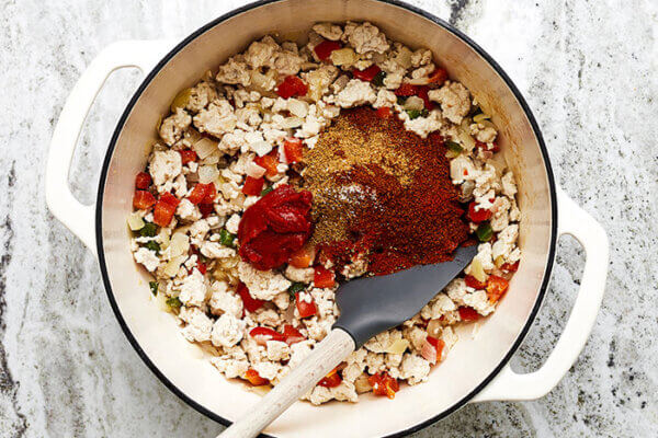 Stirring in spices into a pot of turkey chili