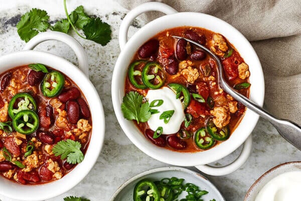 White bowls of turkey chili and sour cream