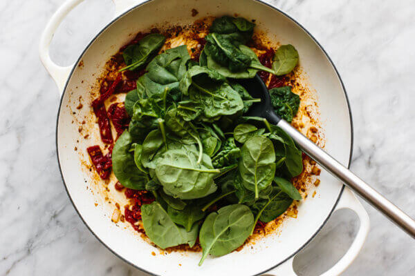 Cooking spinach in a skillet for tuscan chicken