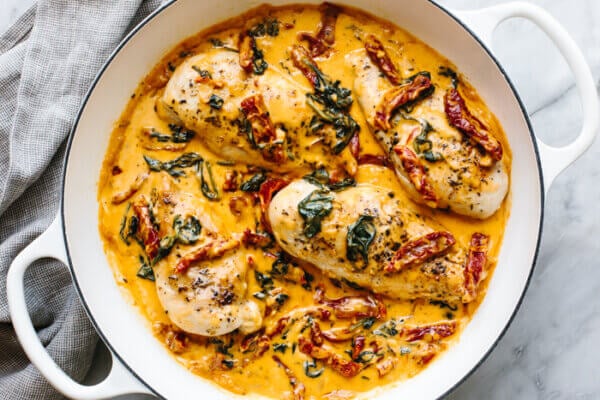 A skillet of tuscan chicken next to a napkin