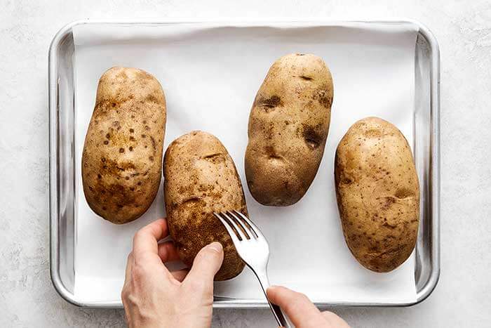 Poking potatoes with a fork.