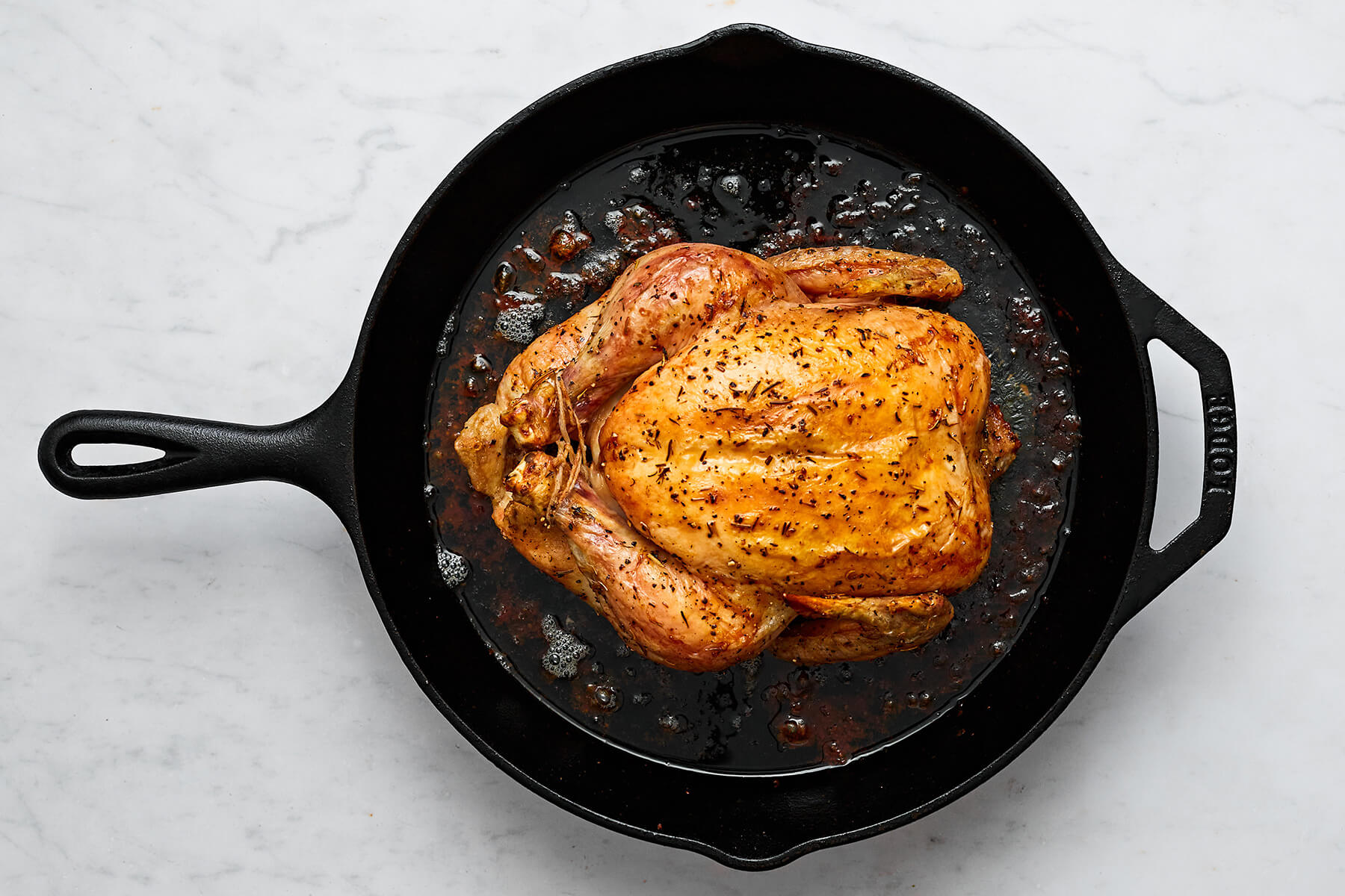 A skillet with a cooked whole roast chicken