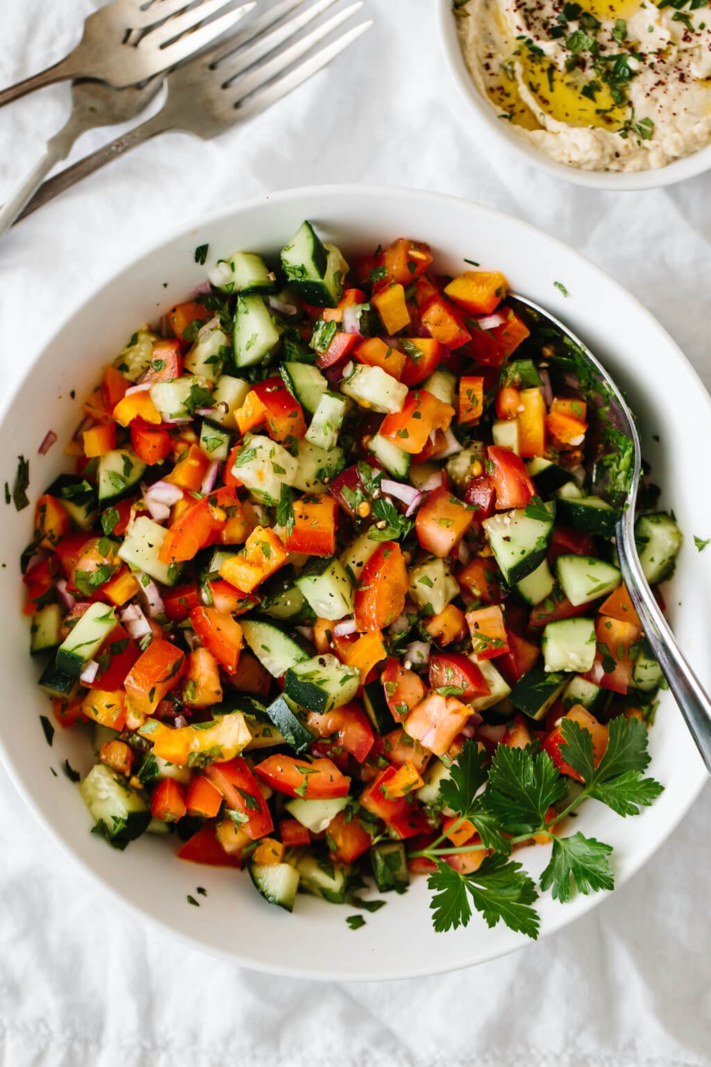 Israeli salad made from tomatoes, cucumber, bell pepper, red onion and herbs in a white bowl.