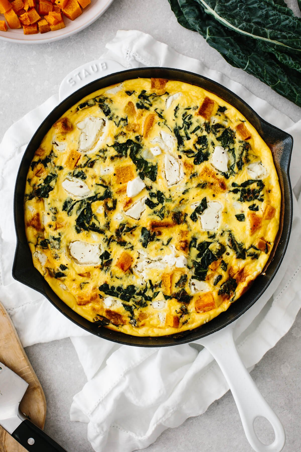 Butternut squash frittata in a white saute pan on a table.