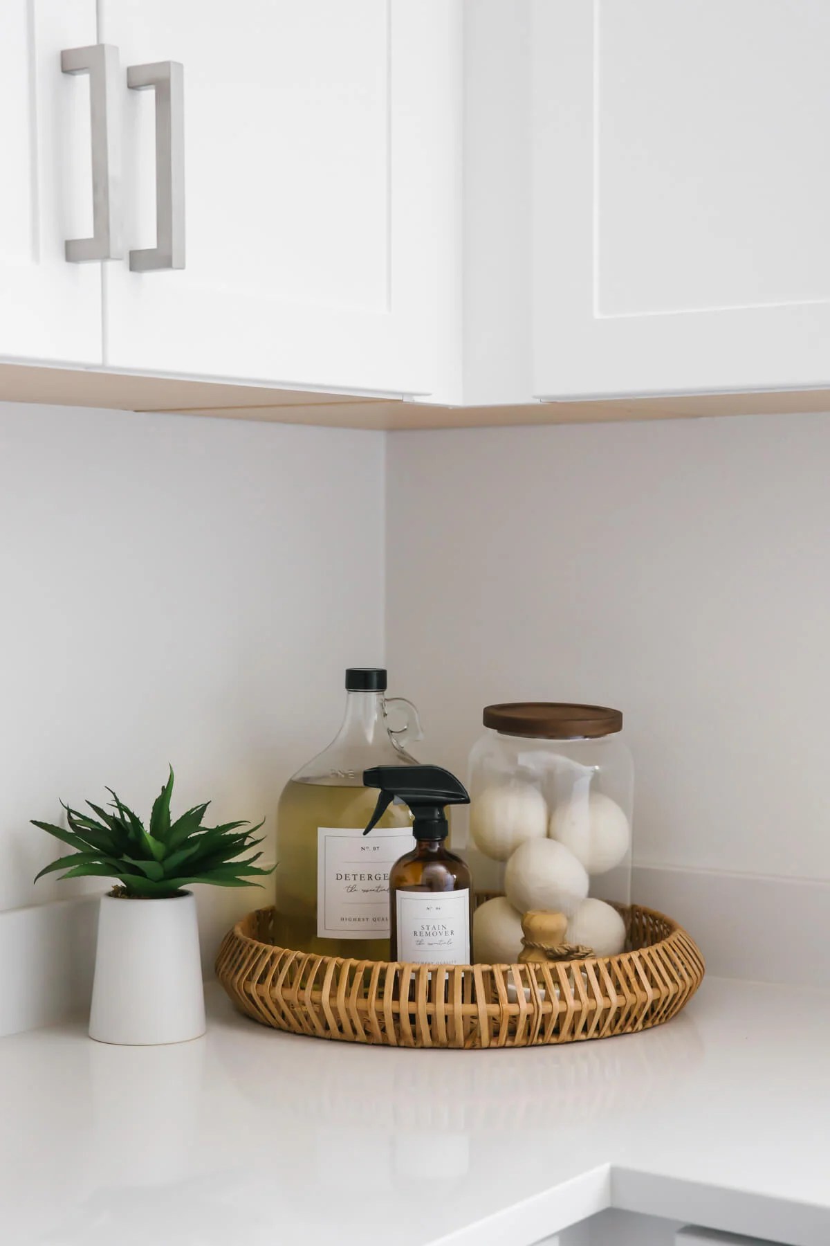 Cleaning materials and dryer balls in wicker basket in laundry room.