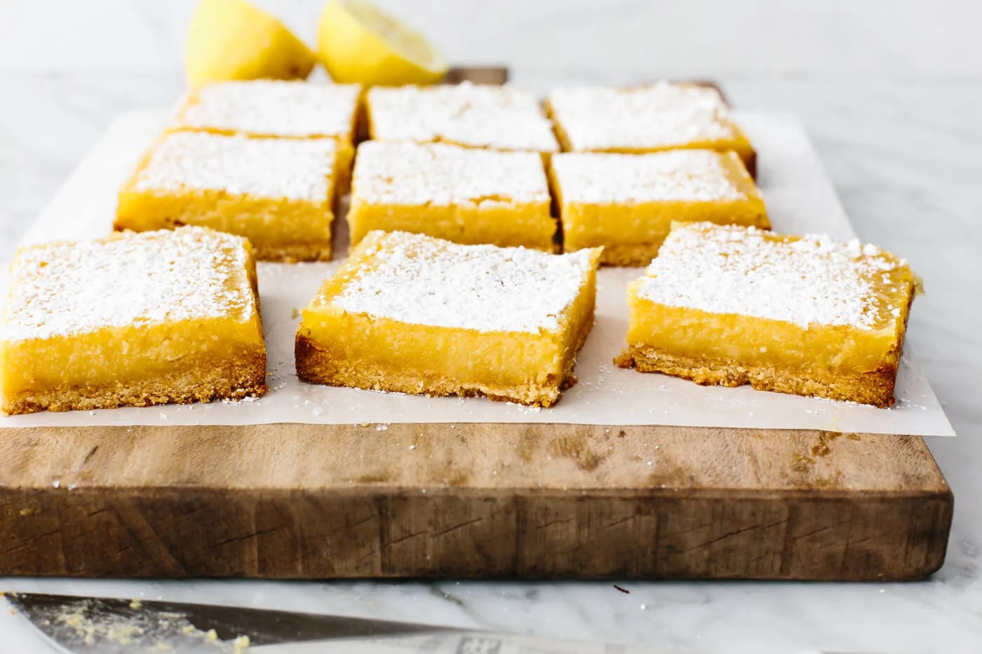 Sliced lemon bars on a wooden board.