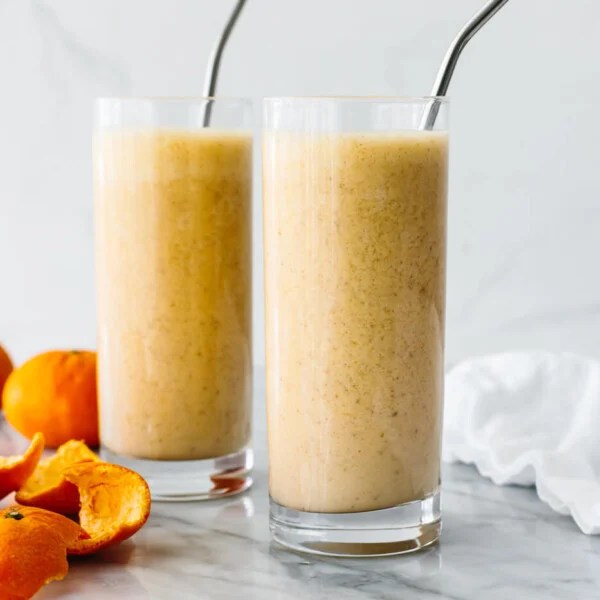 Glasses of mandarin breakfast smoothies next to a napkin.