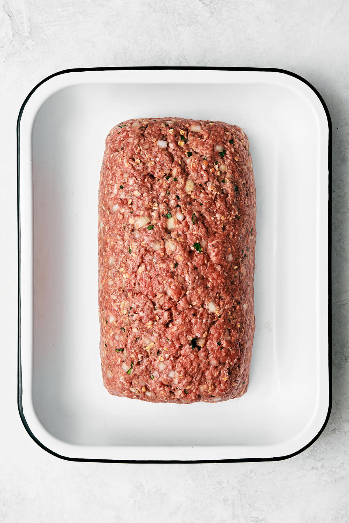 Raw meatloaf in a pan.