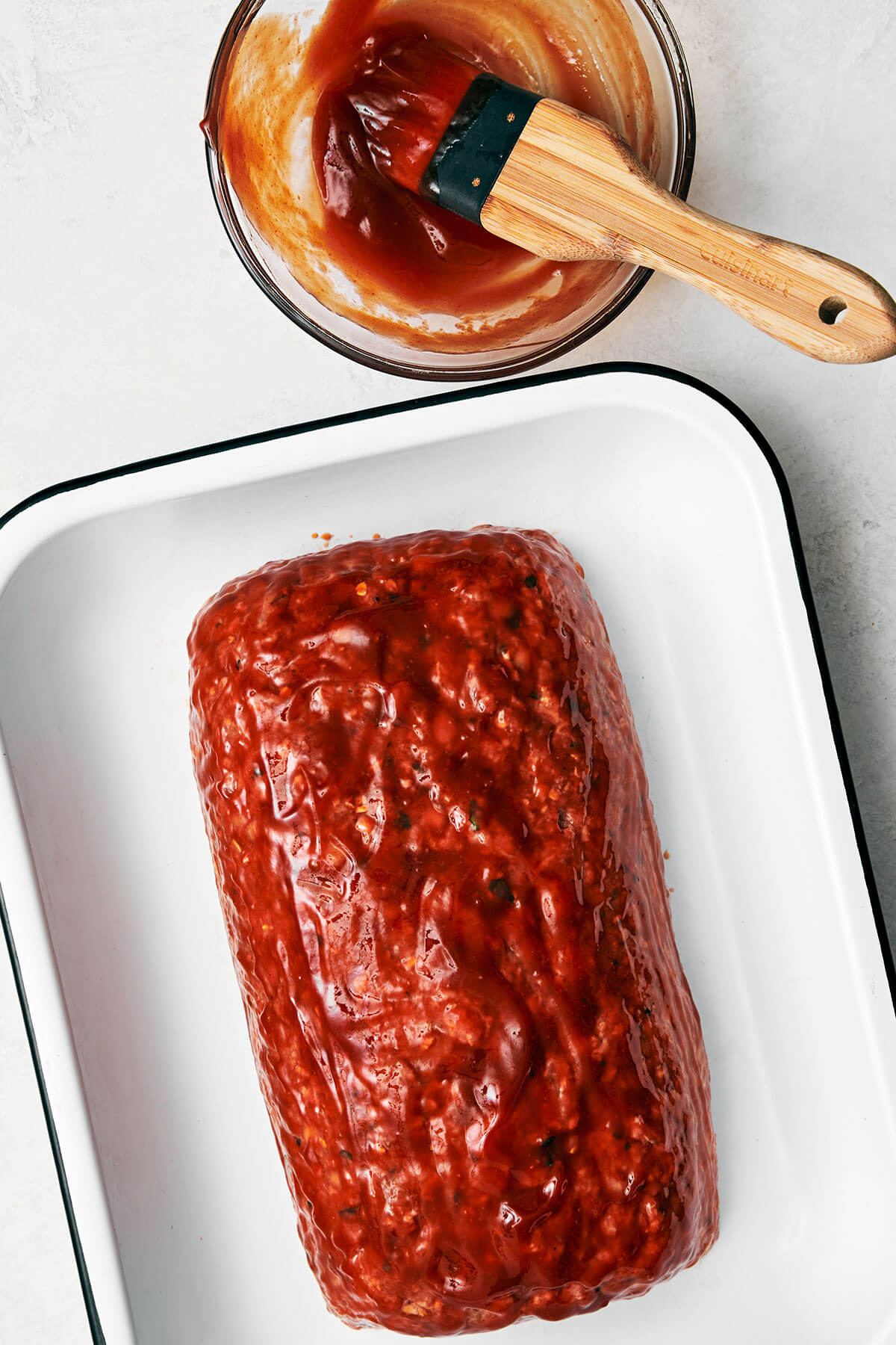 Brushing sauce on meatloaf.