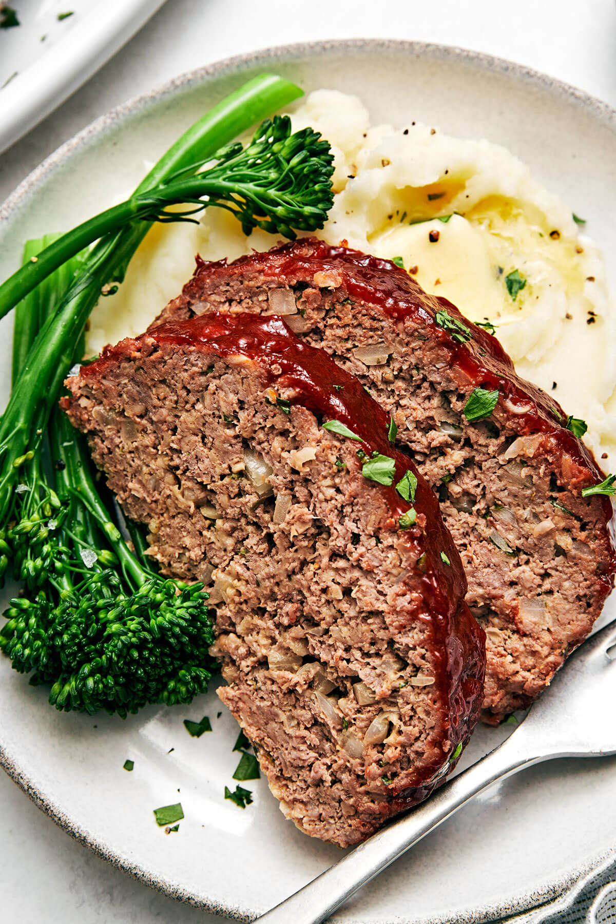 Sliced meatloaf with broccolini and mashed potatoes.