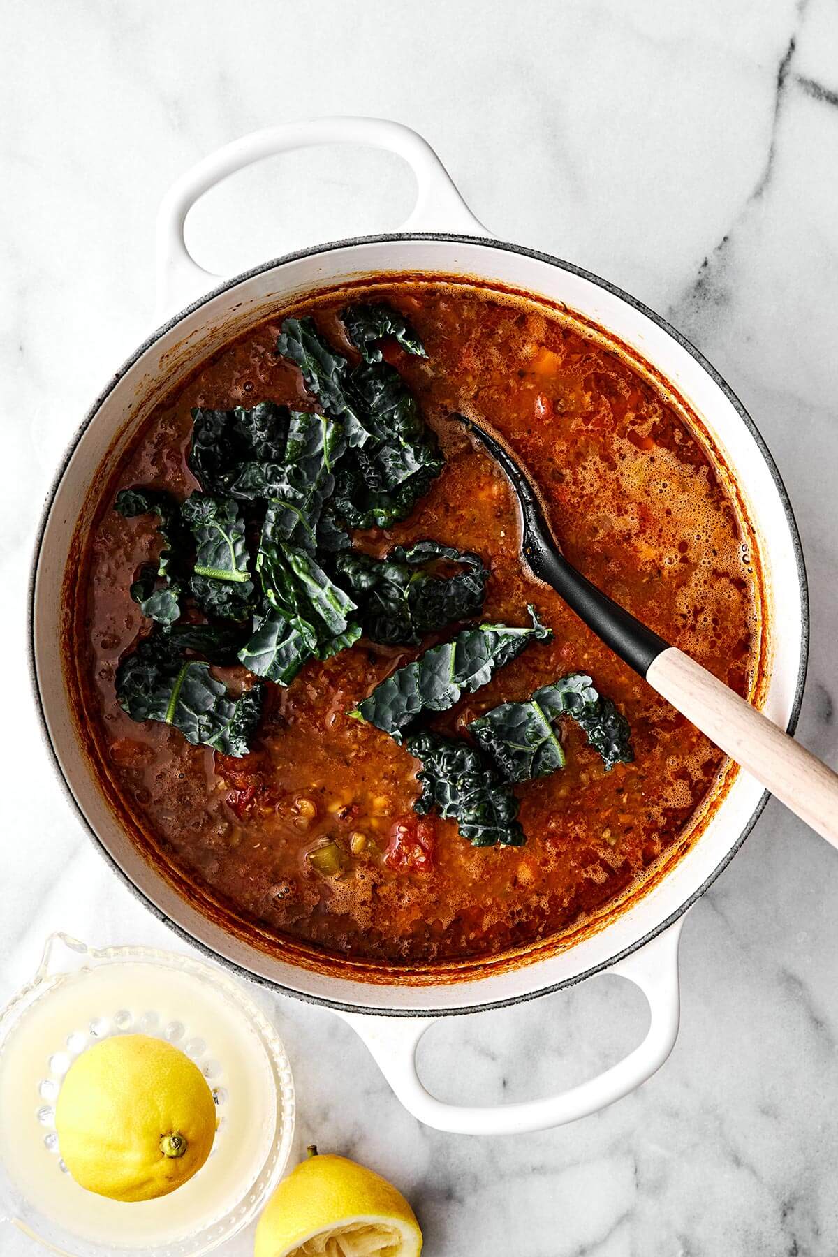 Stirring in kale into lentil soup.