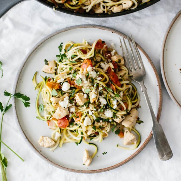 Zucchini noodles with chicken and pico de gallo on a white plate.