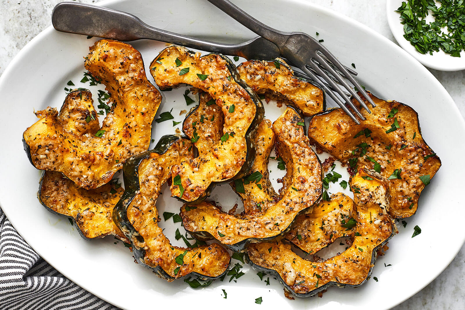 Parmesan herb roasted acorn squash on a white plate with forks