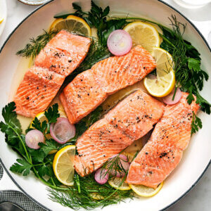 A pan with poached salmon and herbs