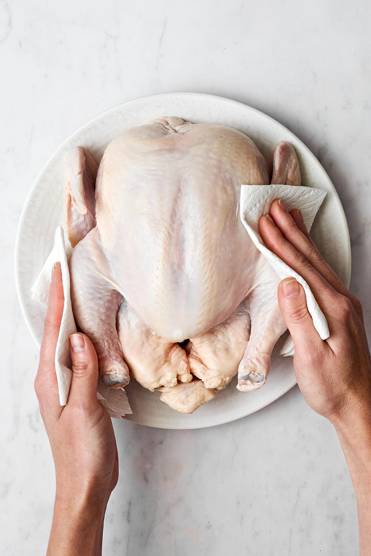 Patting a whole chicken dry before roasting