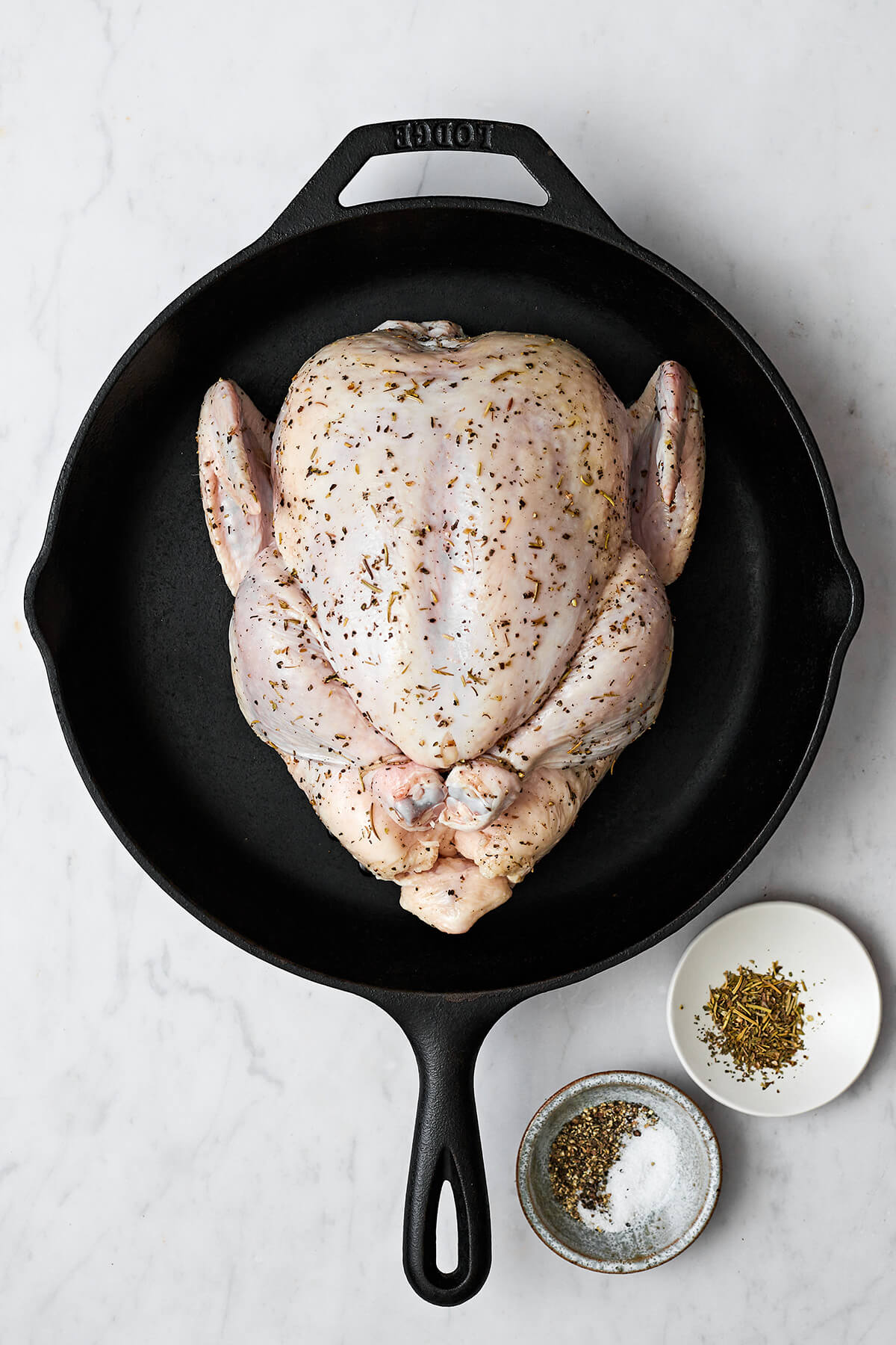 Seasoned whole roast chicken in a skillet