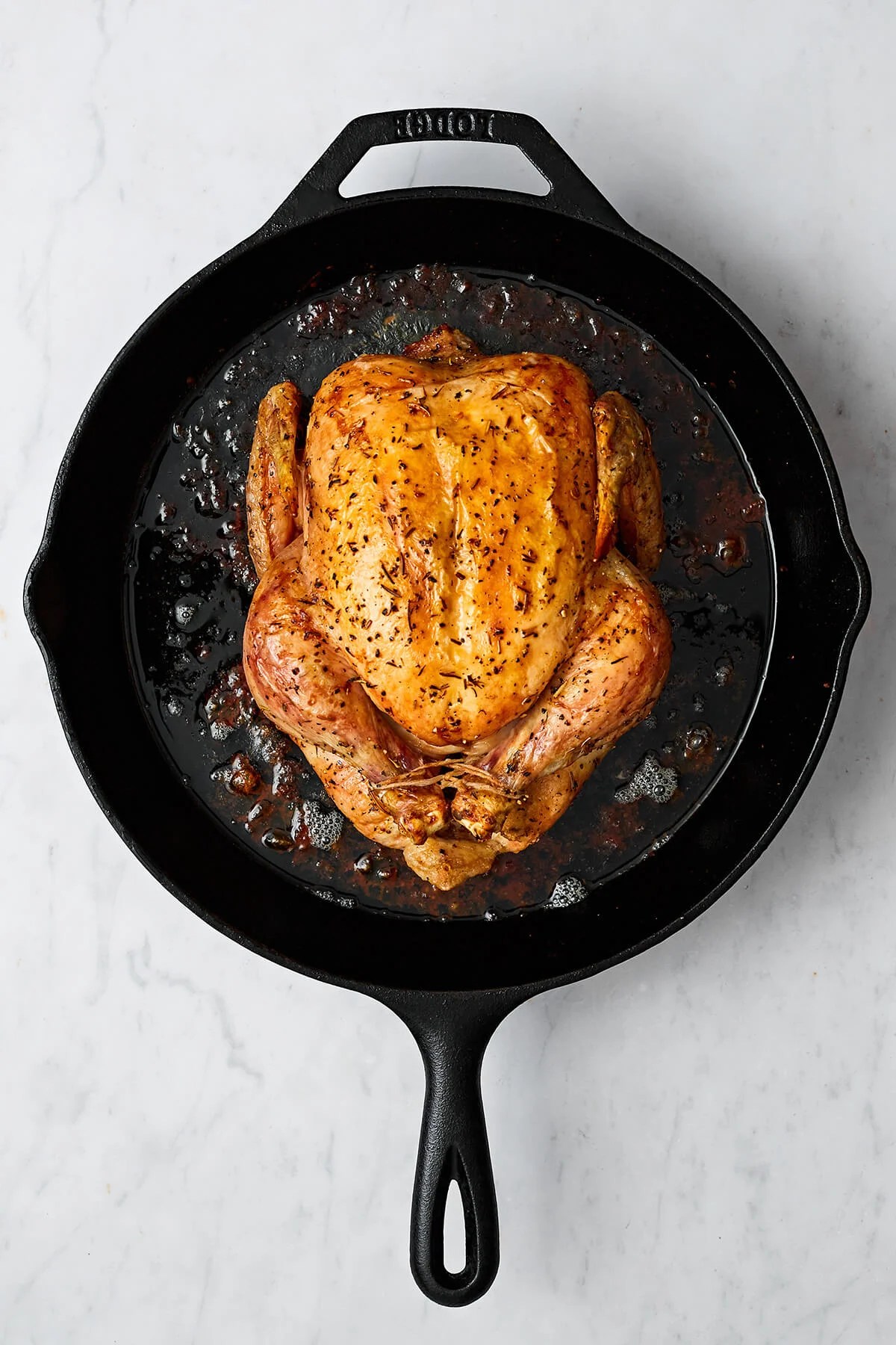 A cooked whole roasted chicken in a skillet