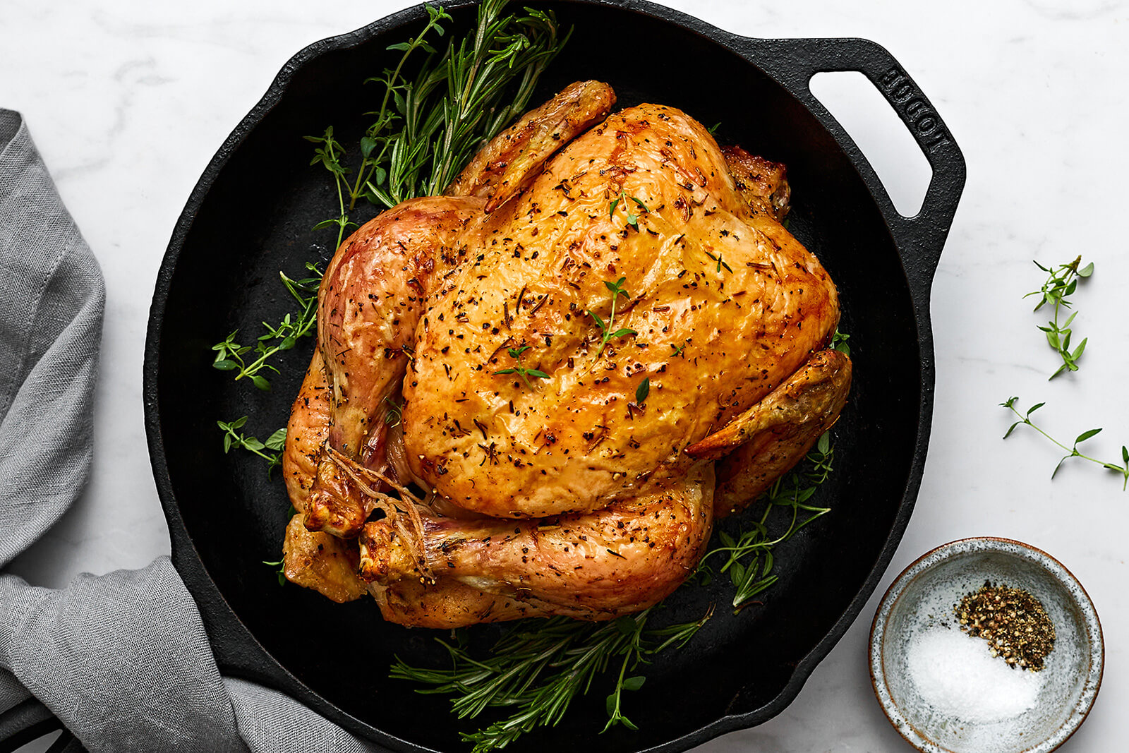 A skillet with roast chicken and herbs