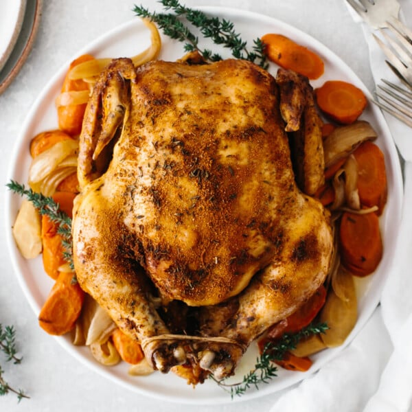 Slow cooker rotisserie chicken on a plate with vegetables.