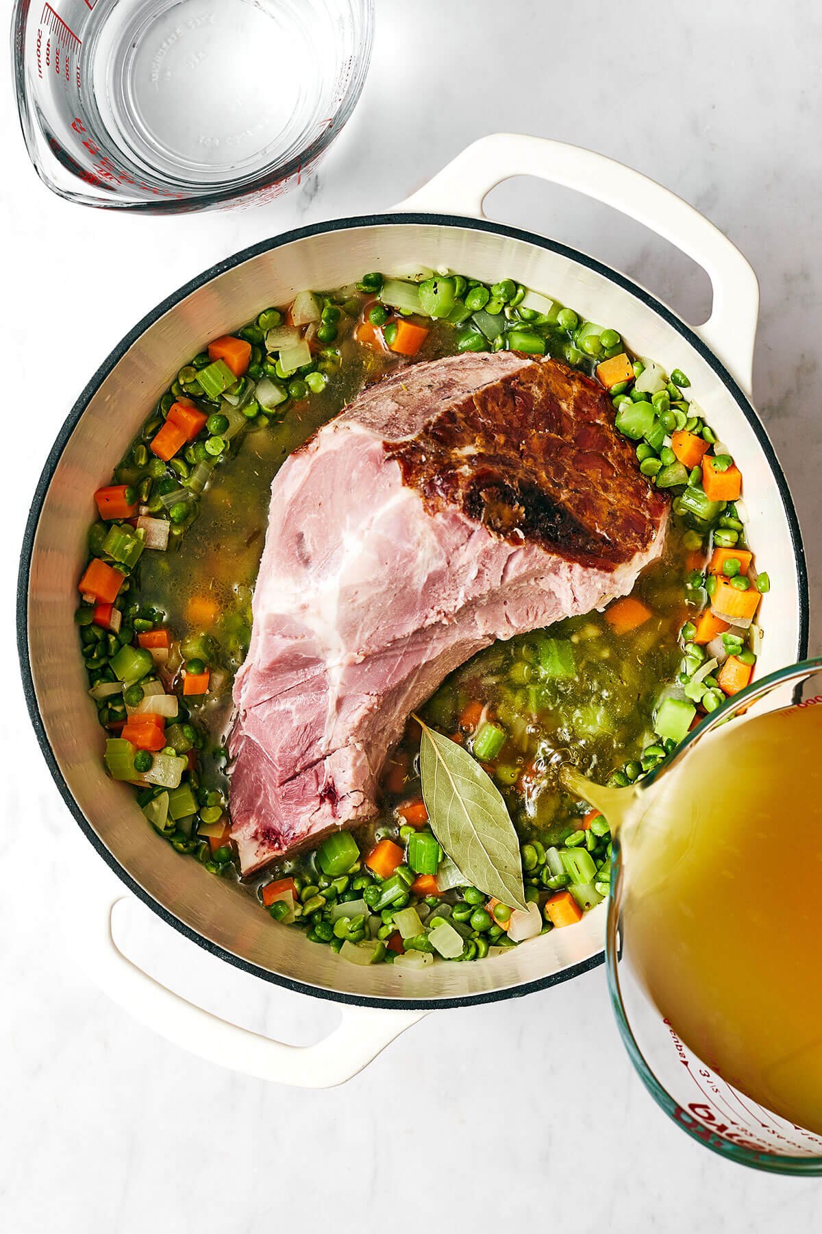 Adding a ham bone into a pot of split pea soup