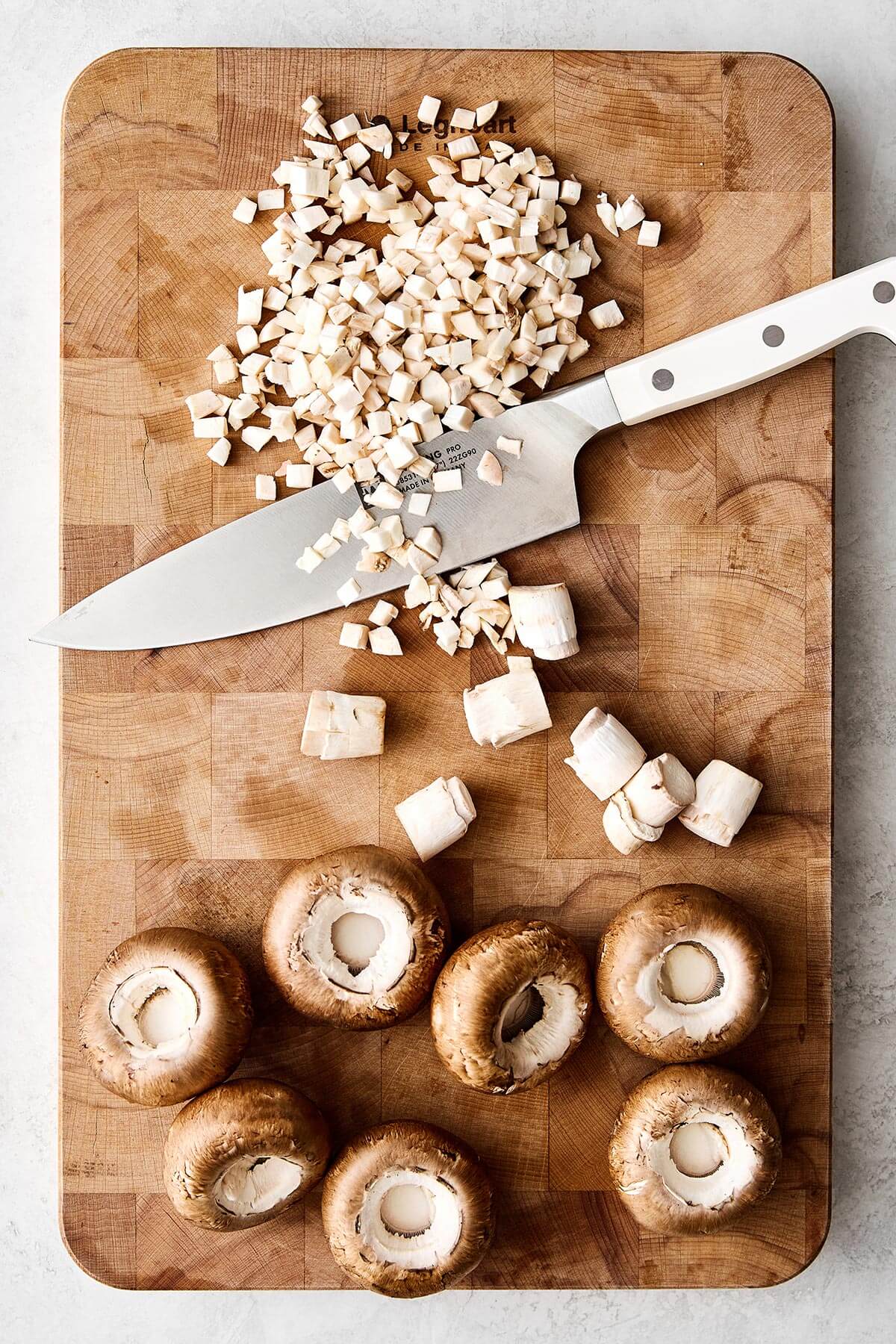 Dicing mushrooms on a board.