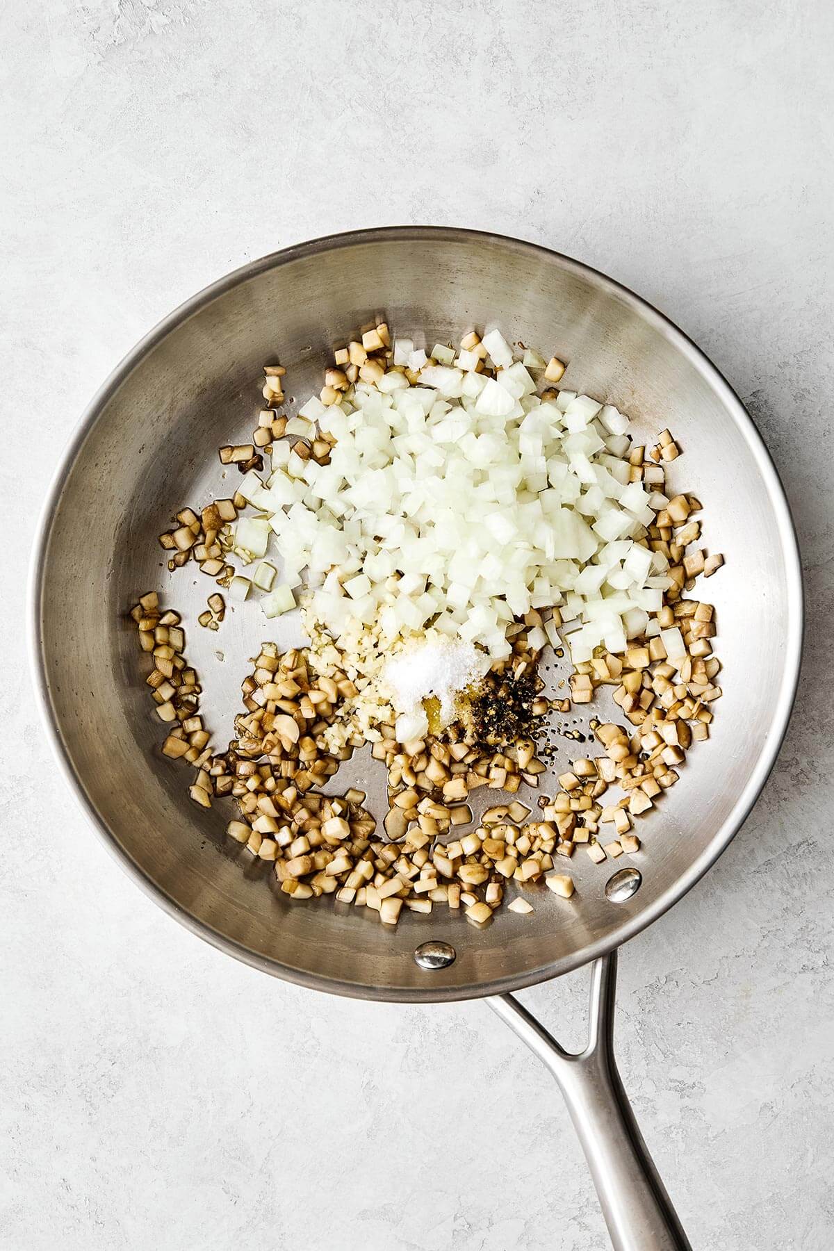 Cooking mushrooms and onion in a pan.