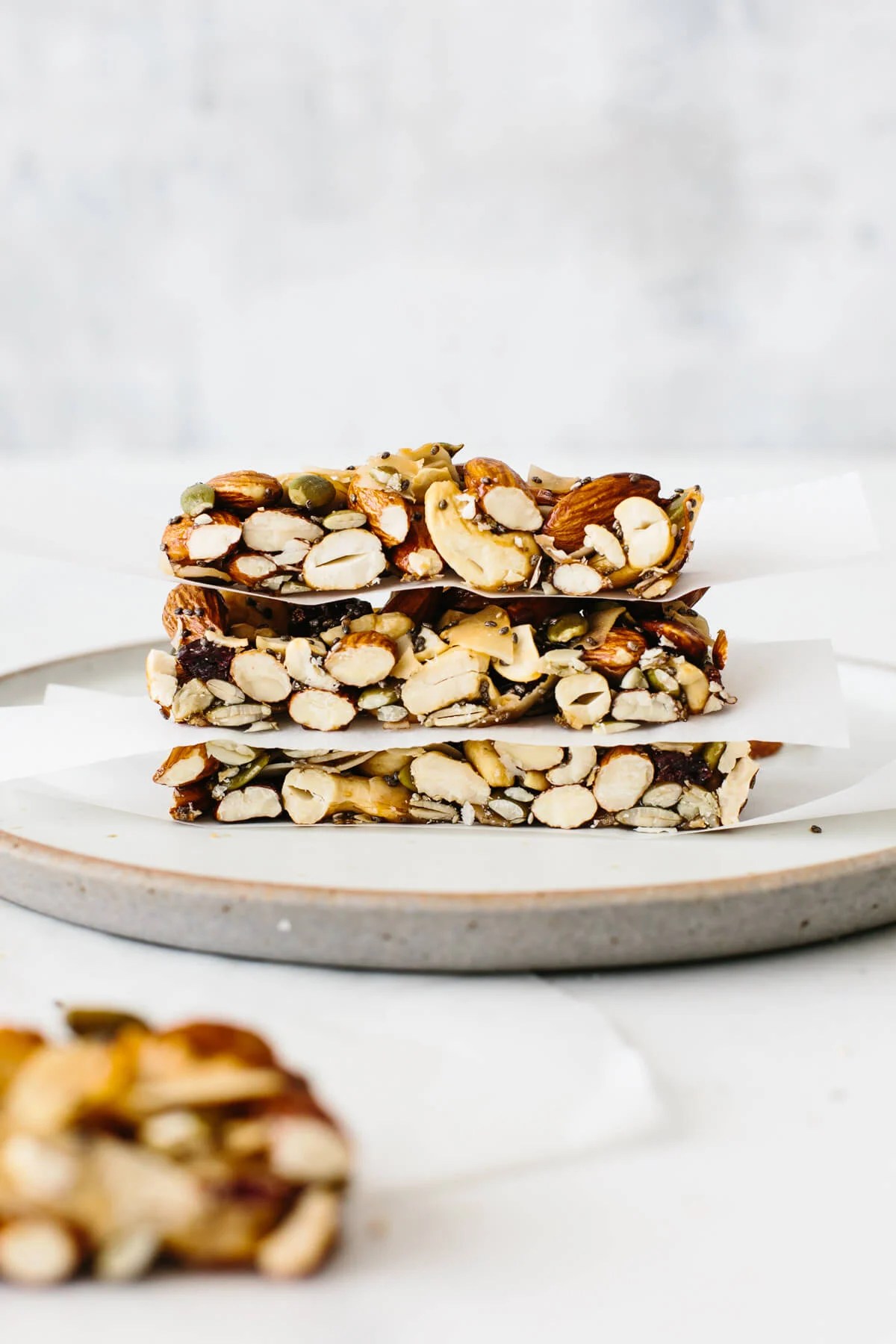 Three granola bars stacked on top of each other on a plate with parchment paper in between.