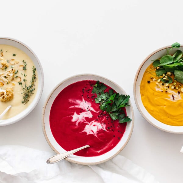 Several bowls of soup on a white table.