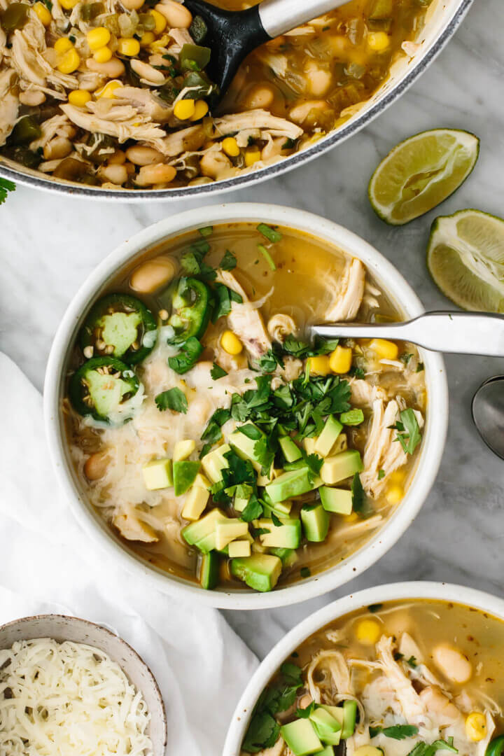 White chicken chili in a bowl next a pot of it.