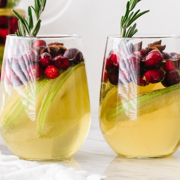 White Christmas sangria in two glasses on a table next to a pitcher.